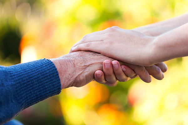 Two persons grasping hands in a display of mutual compassion.